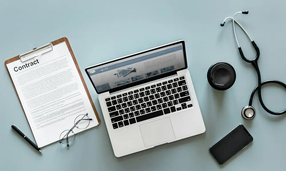 MacBook Pro near black stethoscope and brown clipboard